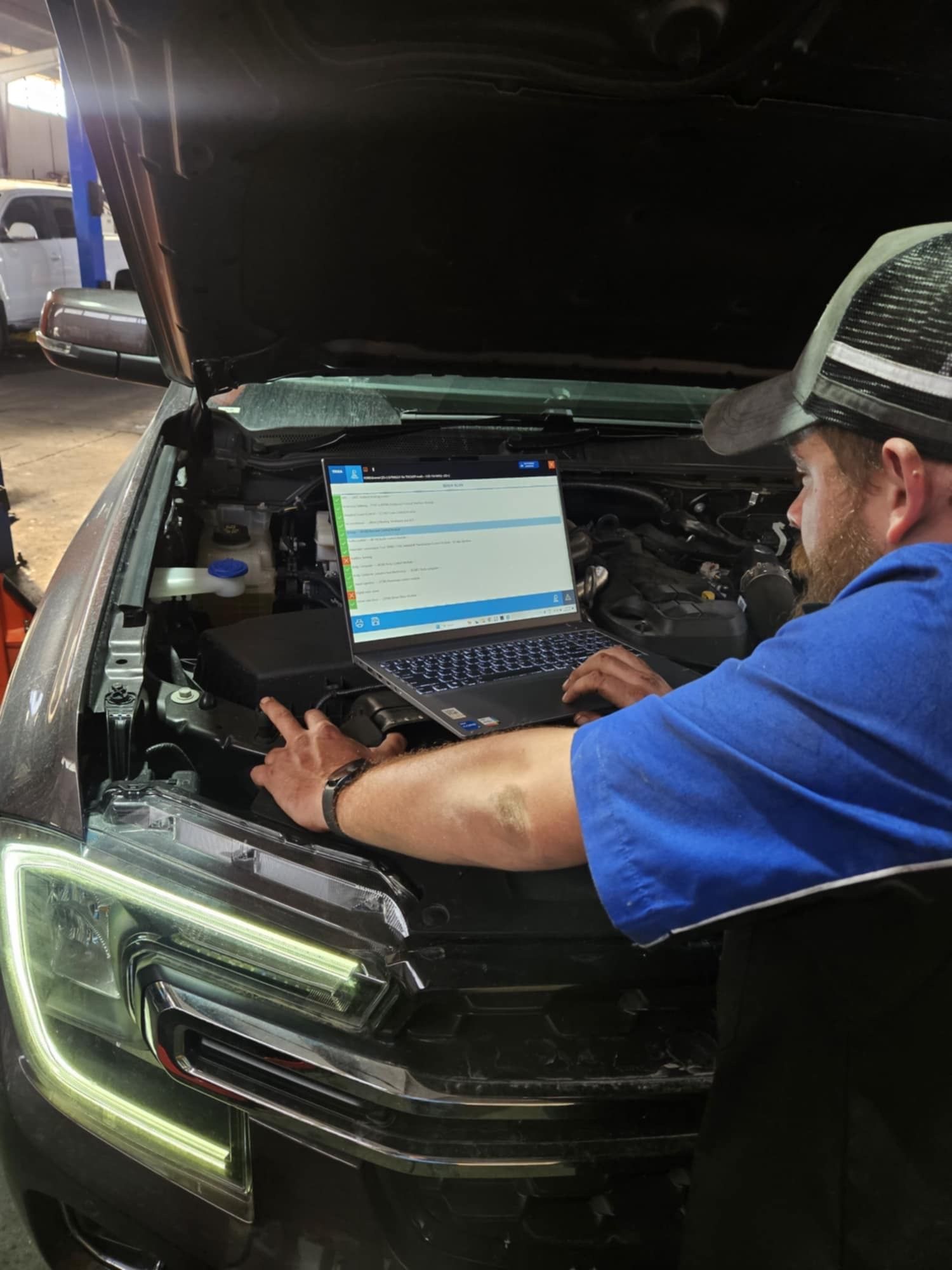 A Man Is Working On A Car With A Laptop — SRG Automotive and Marine in Aitkenvale, QLD