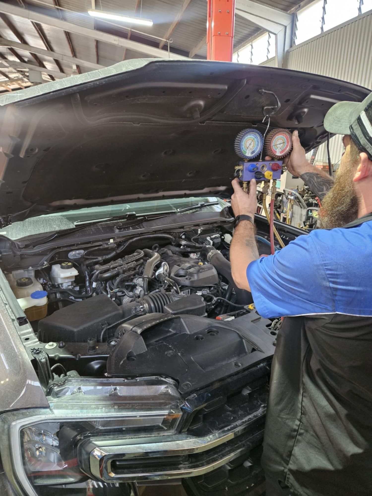 A Close Up Of A Person Holding A Gauge In Front Of A Car Engine — SRG Automotive and Marine in Aitkenvale, QLD