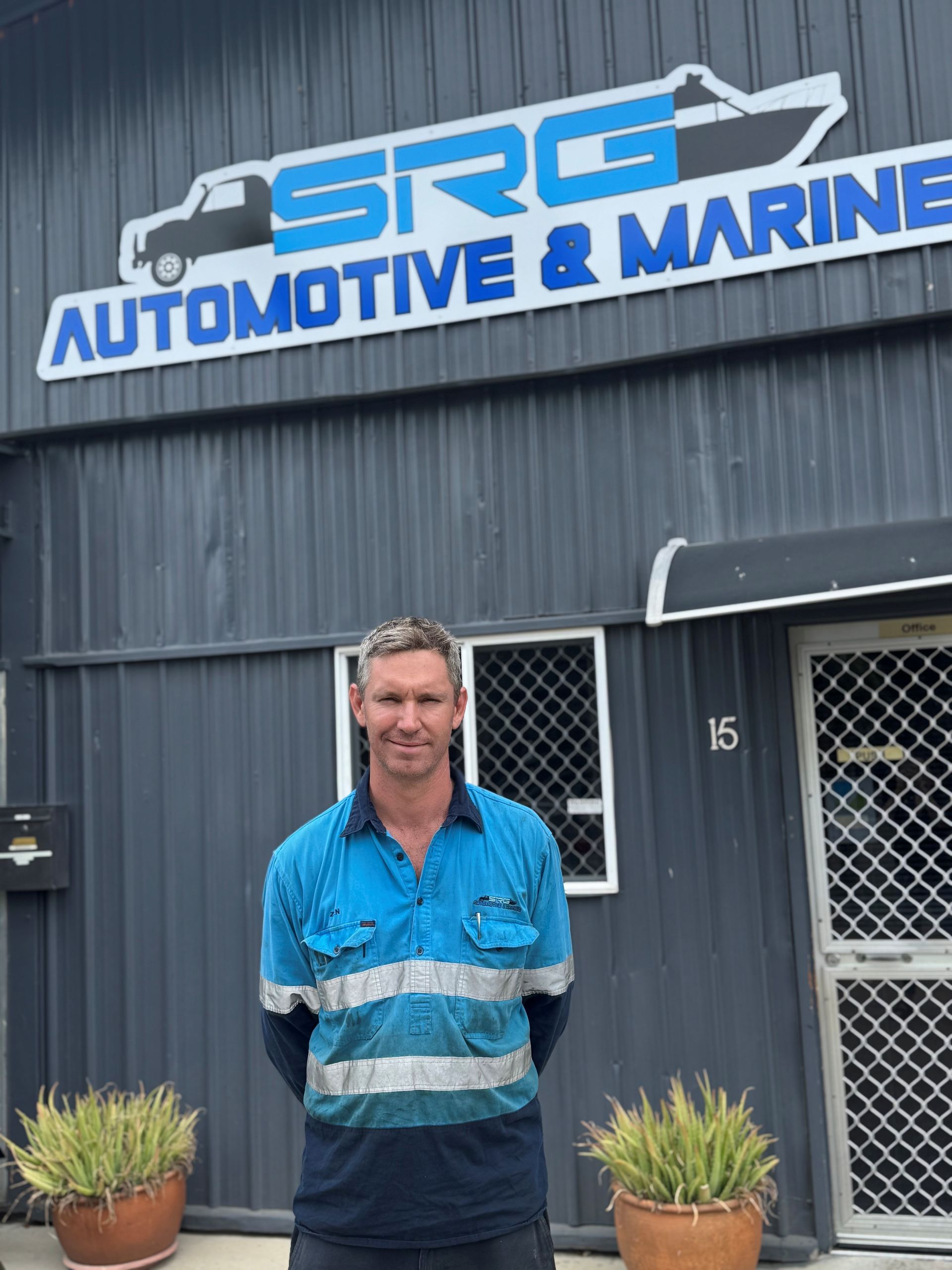 A Man Wearing A Welding Mask Is Working On A Car In A Garage — SRG Automotive and Marine in Aitkenvale, QLD