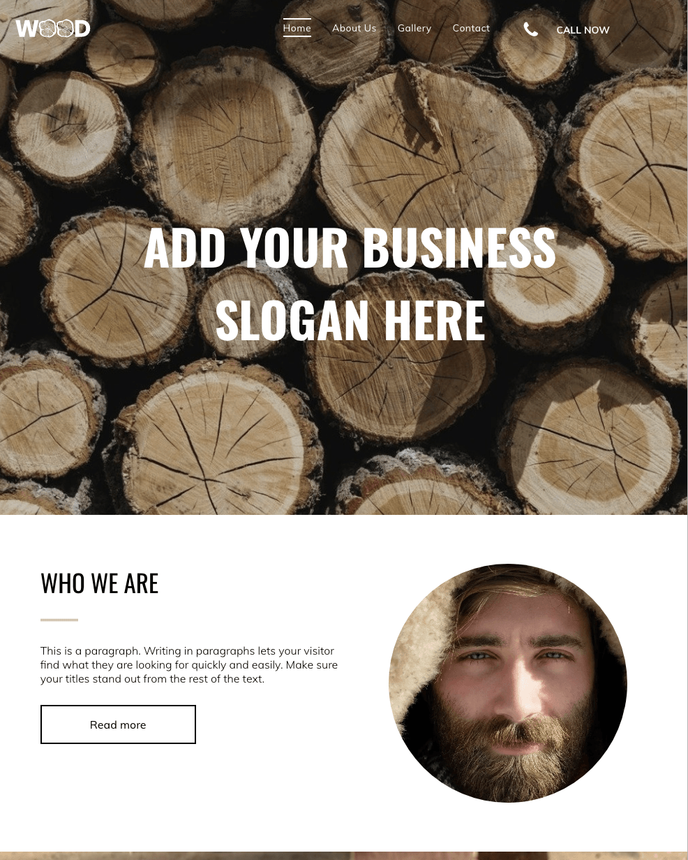 A man with a beard is standing in front of a pile of logs.