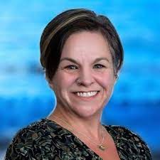 A woman is smiling for the camera in front of a blue background.
