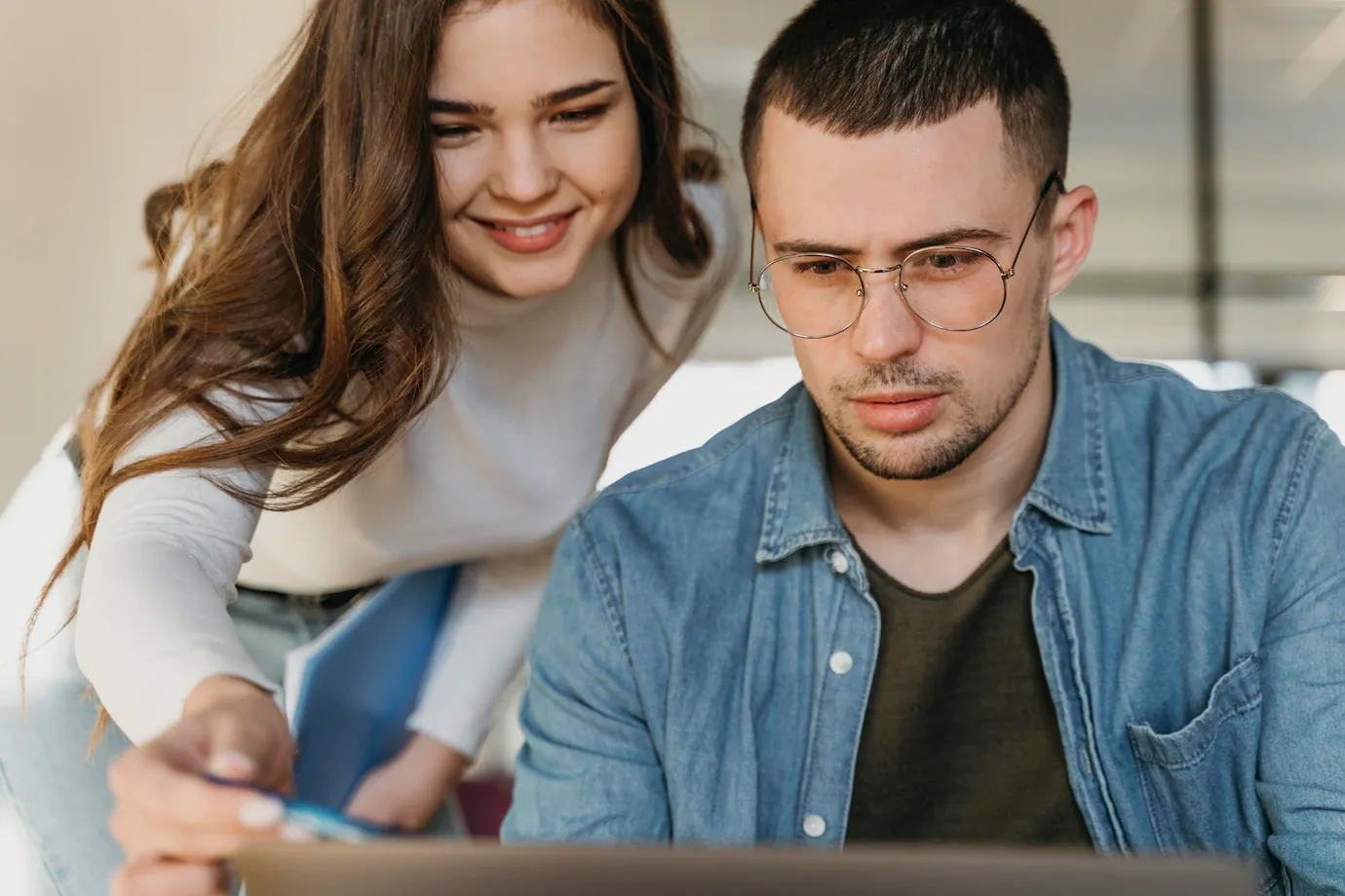 A man and a woman are looking at a laptop computer.