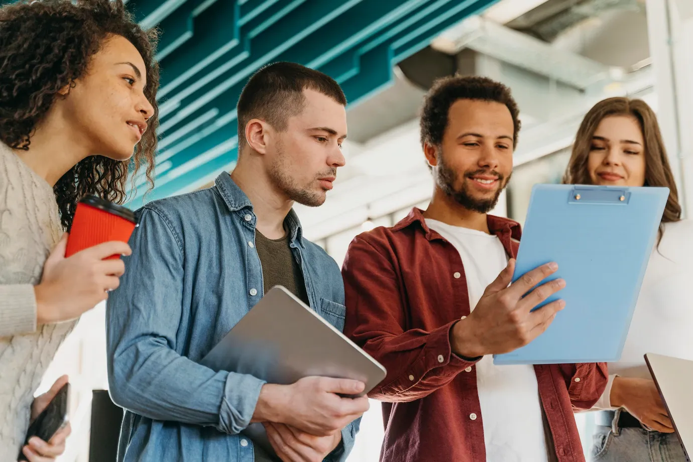 A group of people are standing next to each other looking at a clipboard.