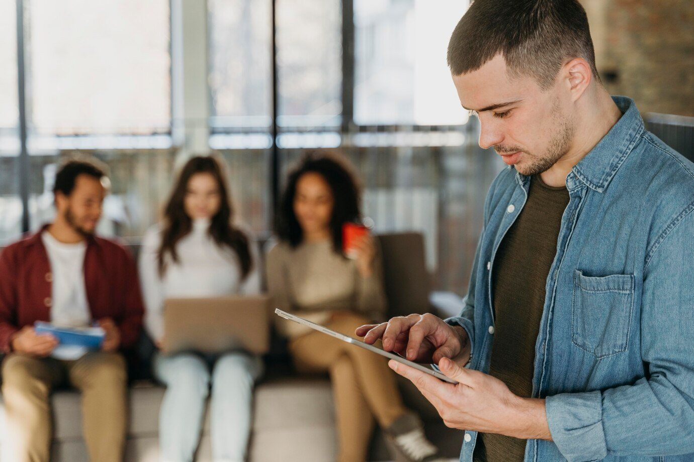 A man is holding a tablet in front of a group of people.