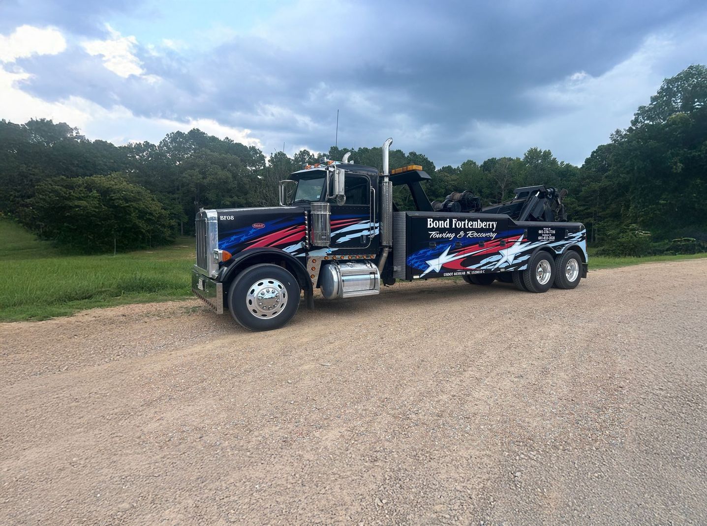 A truck is towing a container on a trailer in a gravel lot.