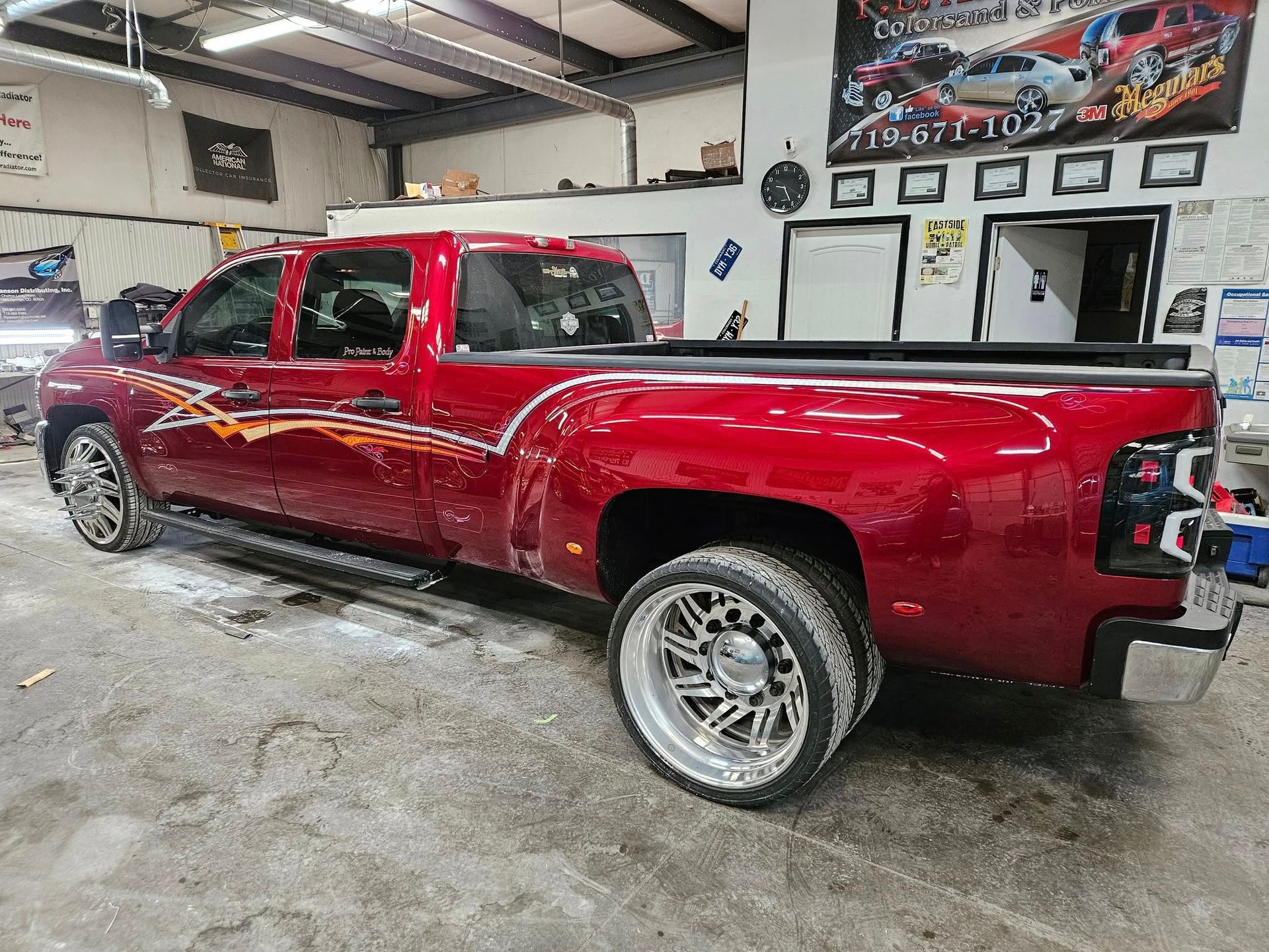 Red customized dually truck with a graphic design in a garage.