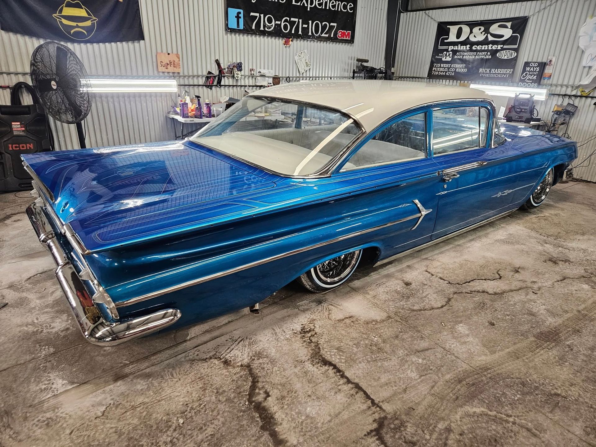 Blue vintage car with white roof in a garage.