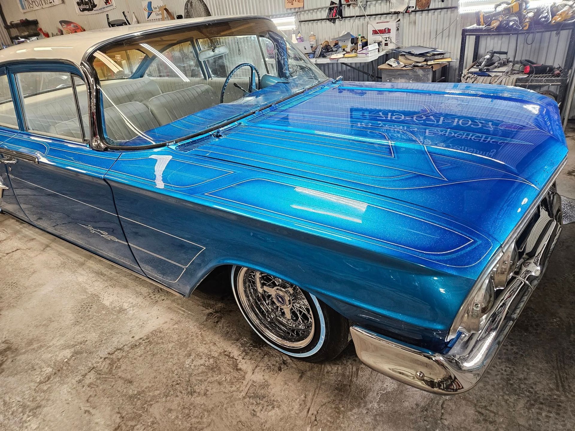 Blue classic car with intricate designs in a garage.