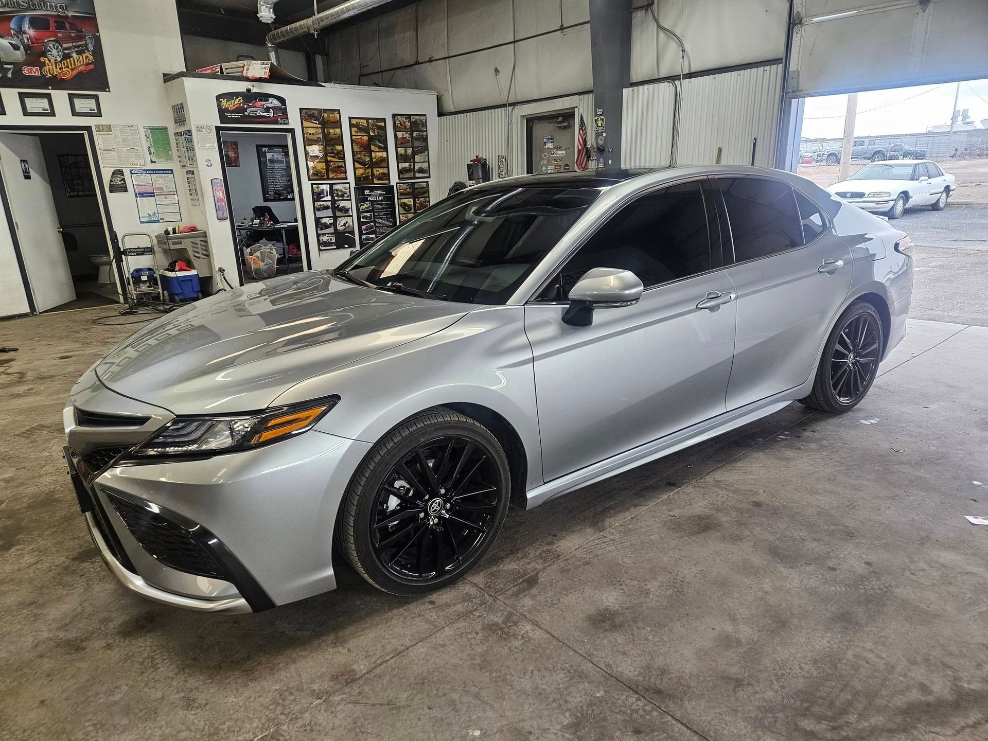 Silver Toyota Camry with black rims, parked inside a garage.