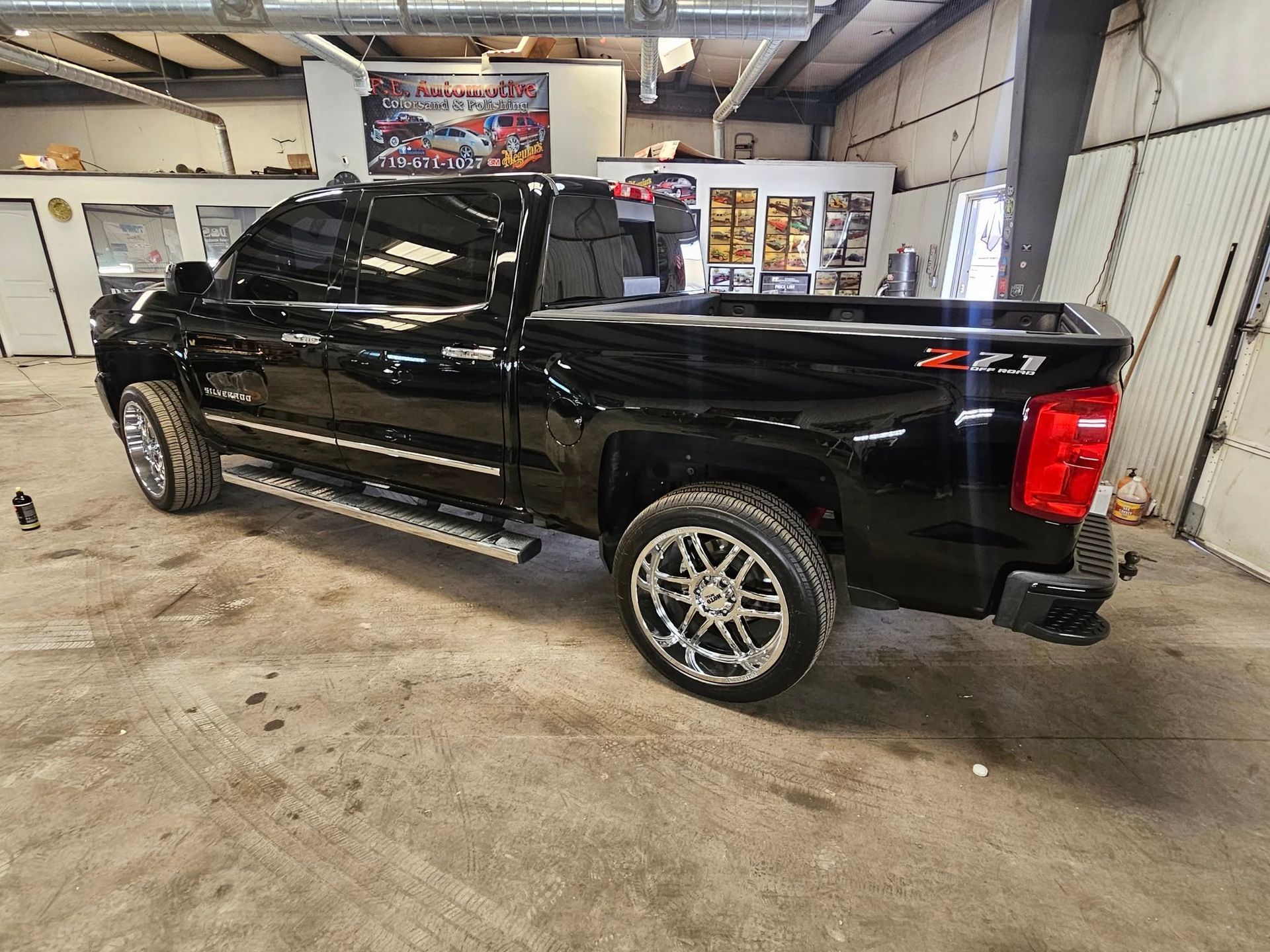 Black pickup truck with tinted windows and chrome wheels in a garage setting.
