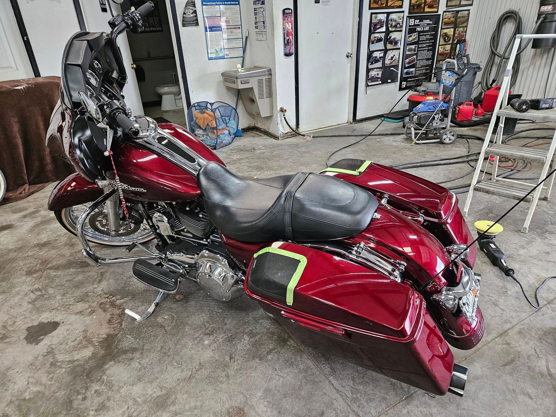 Red Harley-Davidson motorcycle in a garage. It has a black seat and saddlebags.