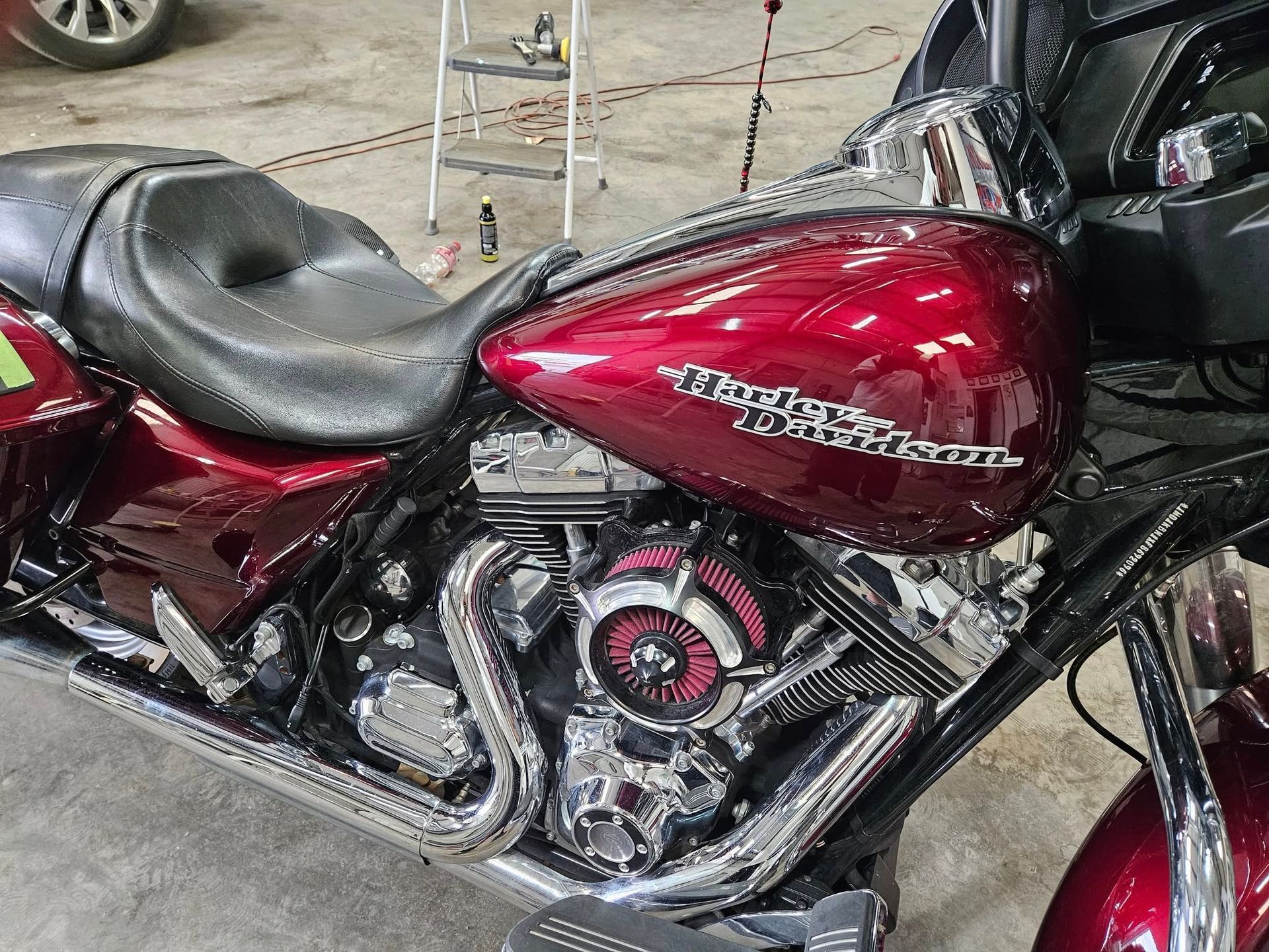 Red and chrome Harley-Davidson motorcycle with black seat, in a garage.