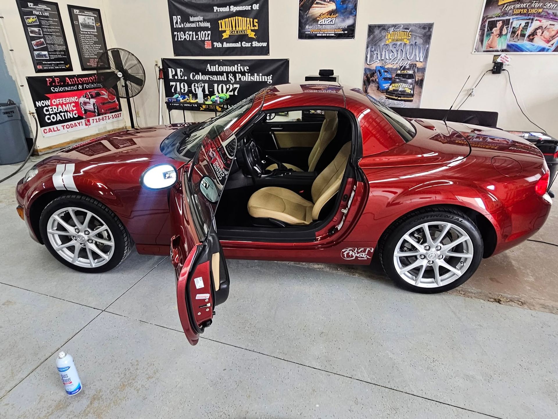 Red sports car with open doors, in a garage.