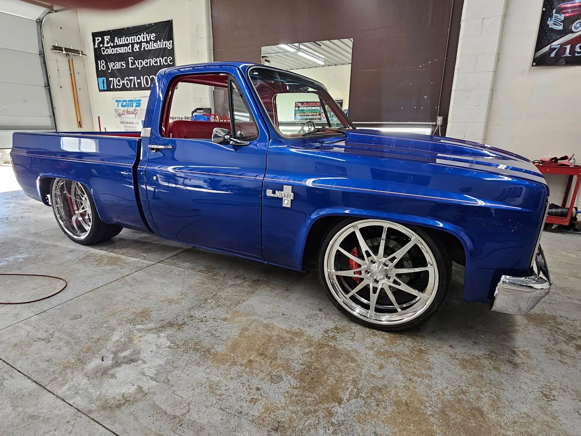 Blue classic Chevrolet pickup truck, custom wheels, lowered suspension, indoors.