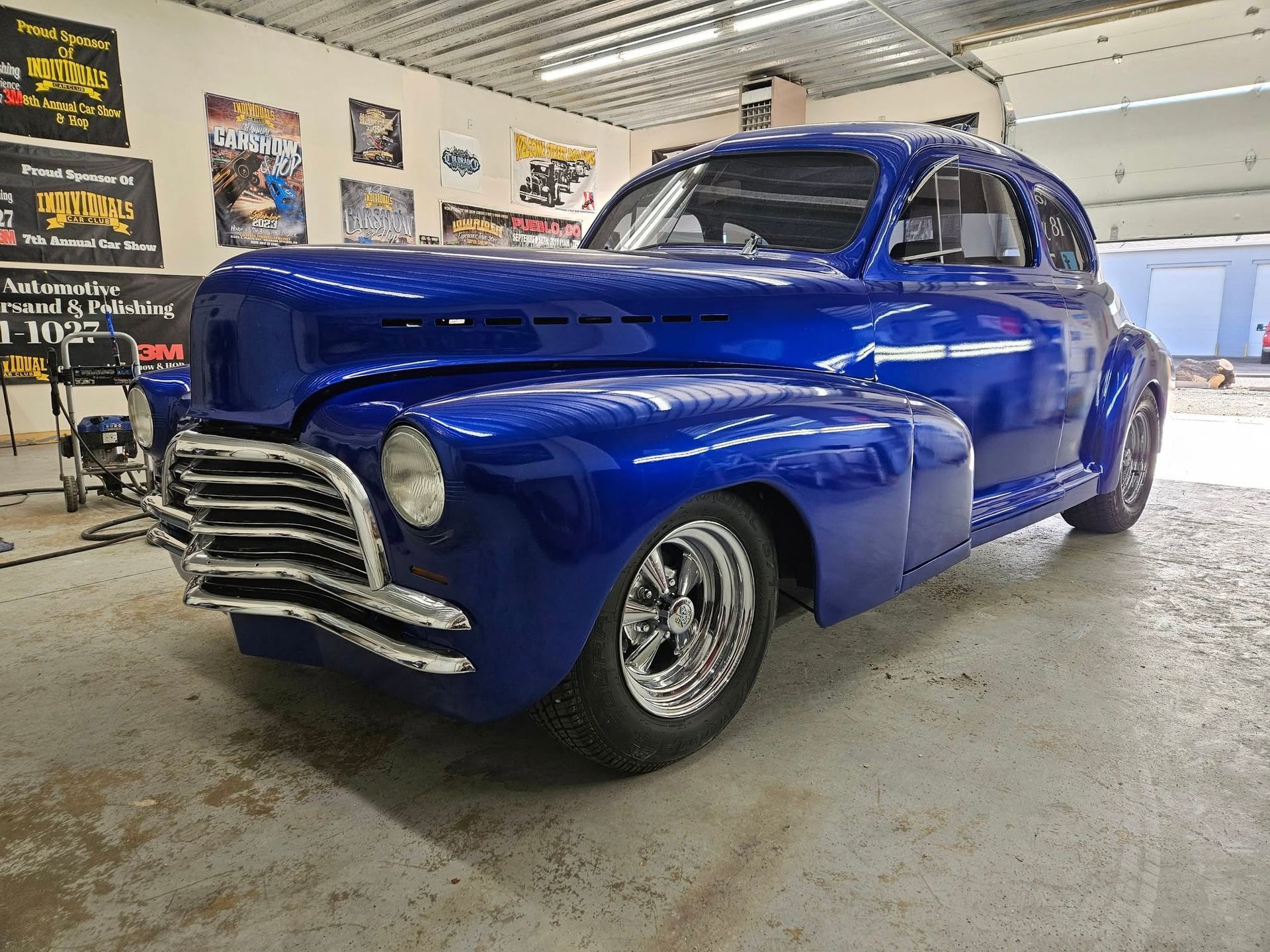 Blue classic car with chrome accents in a garage.