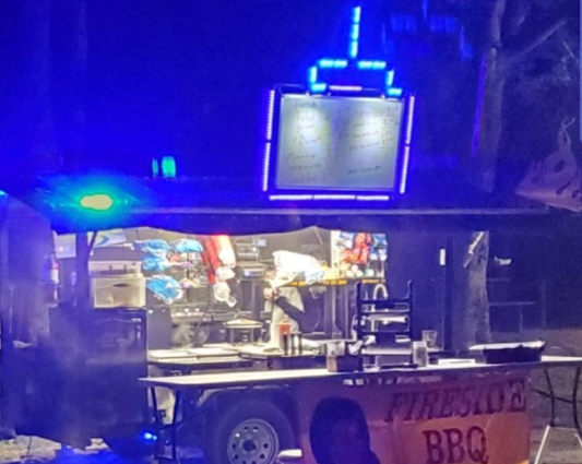 A fireside bbq trailer is lit up at night