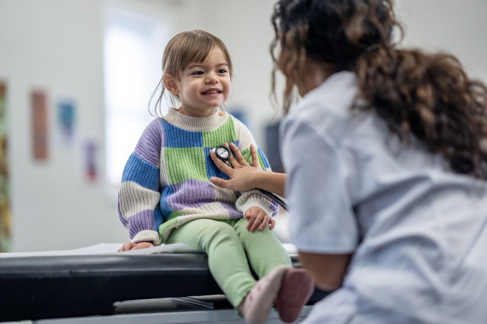 A little girl is being examined by a doctor with a stethoscope.