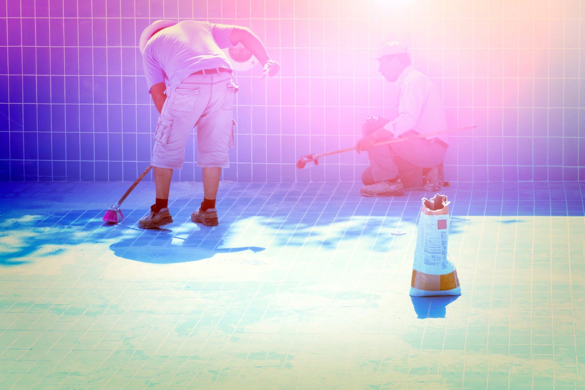 Two men put the tiles on the bottom of the pool.
