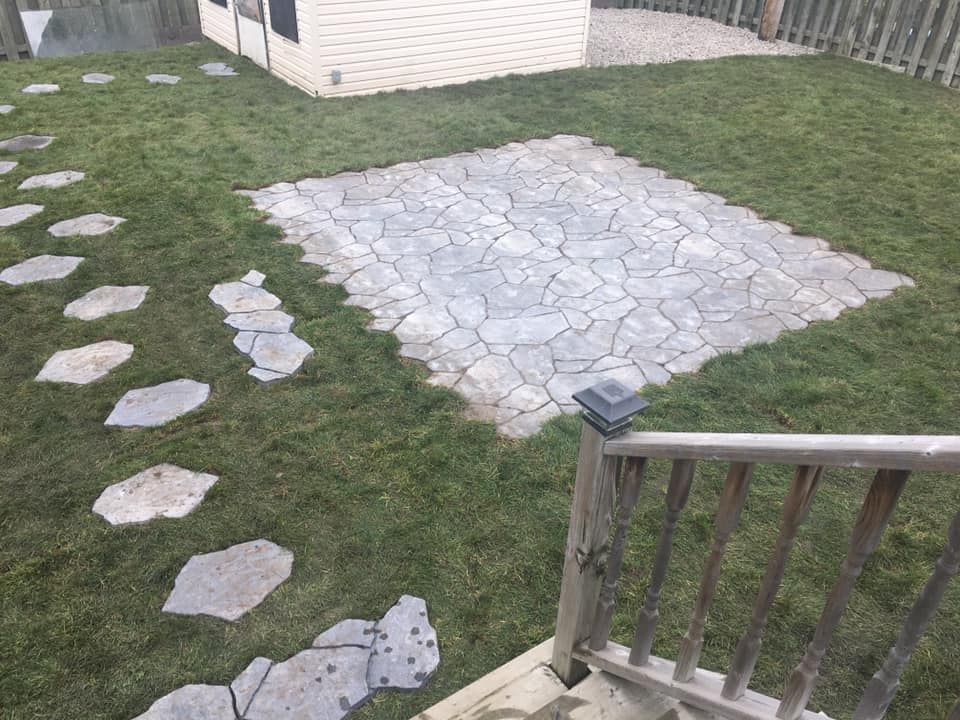 Une cour arrière avec une allée en pierre et un cabanon en arrière-plan.