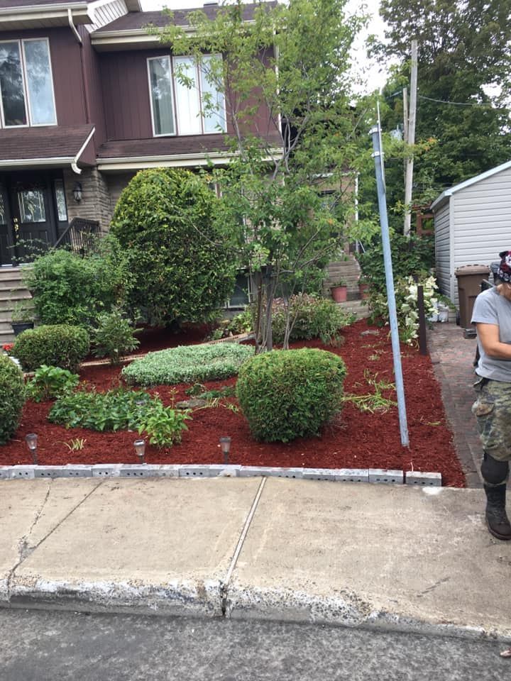 Un homme se tient sur le trottoir devant une maison.