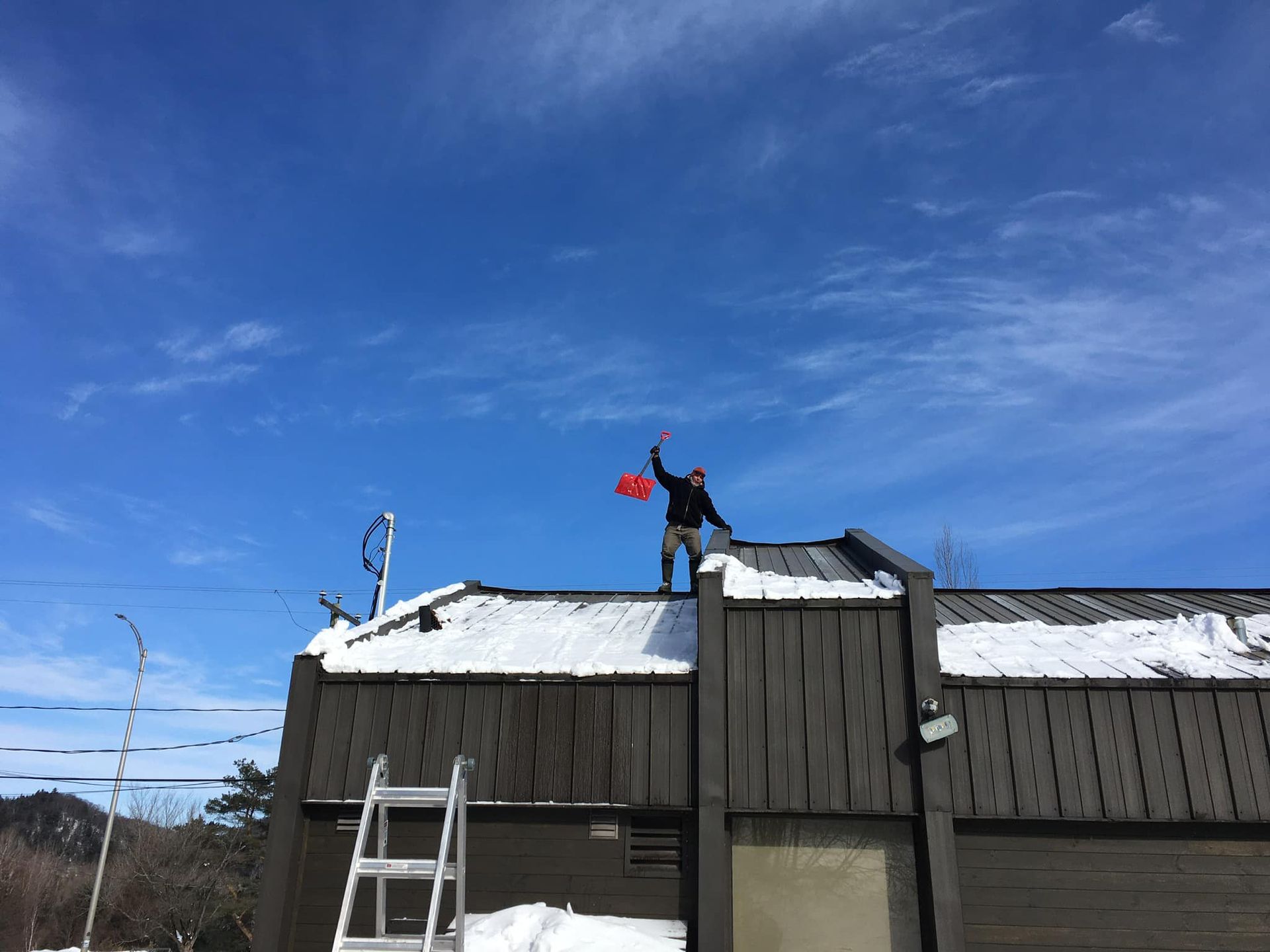 Un homme se tient au sommet d'un toit couvert de neige.