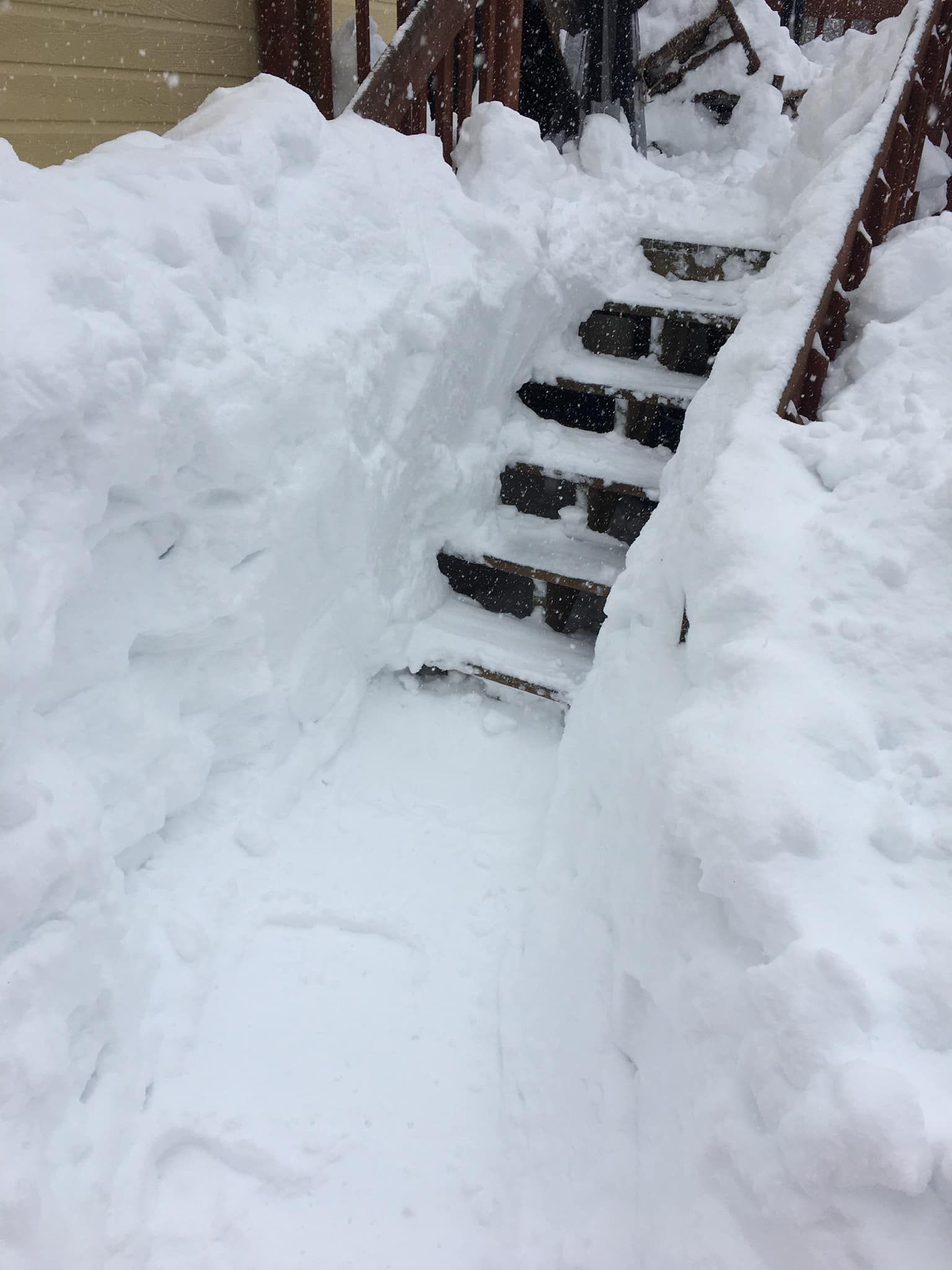 Les escaliers sont recouverts de neige et il y a beaucoup de neige au sol.