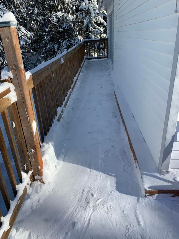 Une passerelle enneigée menant à une maison avec une balustrade en bois