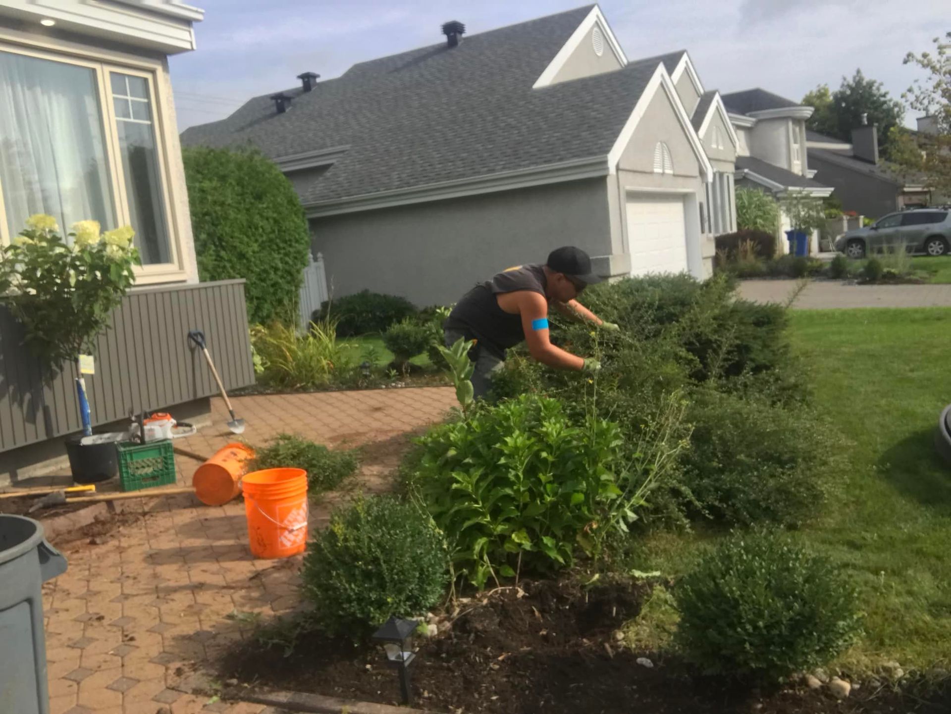 Un homme travaille dans un jardin devant une maison