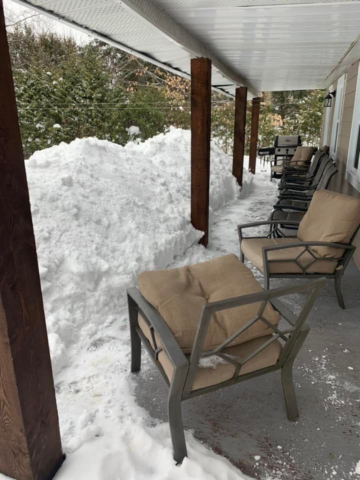 Un porche avec des chaises et des poufs recouverts de neige