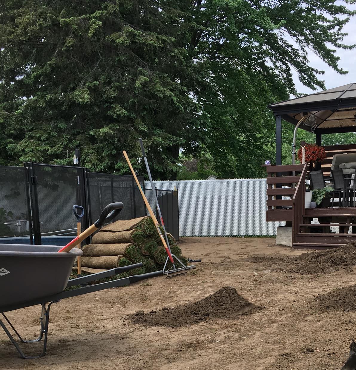 Une brouette est posée dans la terre devant un belvédère.