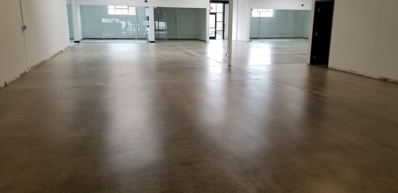 Empty interior space with polished concrete floor, white walls, and glass partitions.