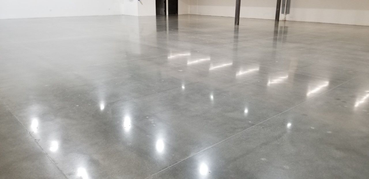 Polished concrete floor reflecting light in an empty, open space.