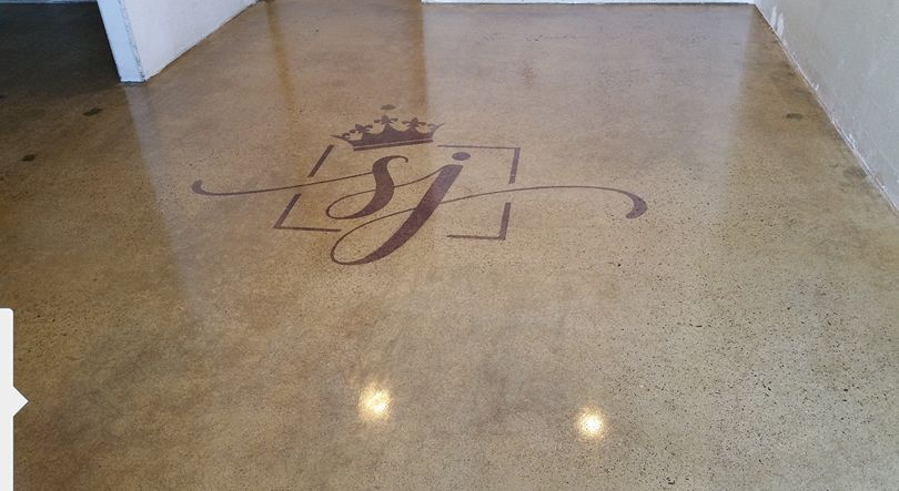 Polished concrete floor with a logo in brown.