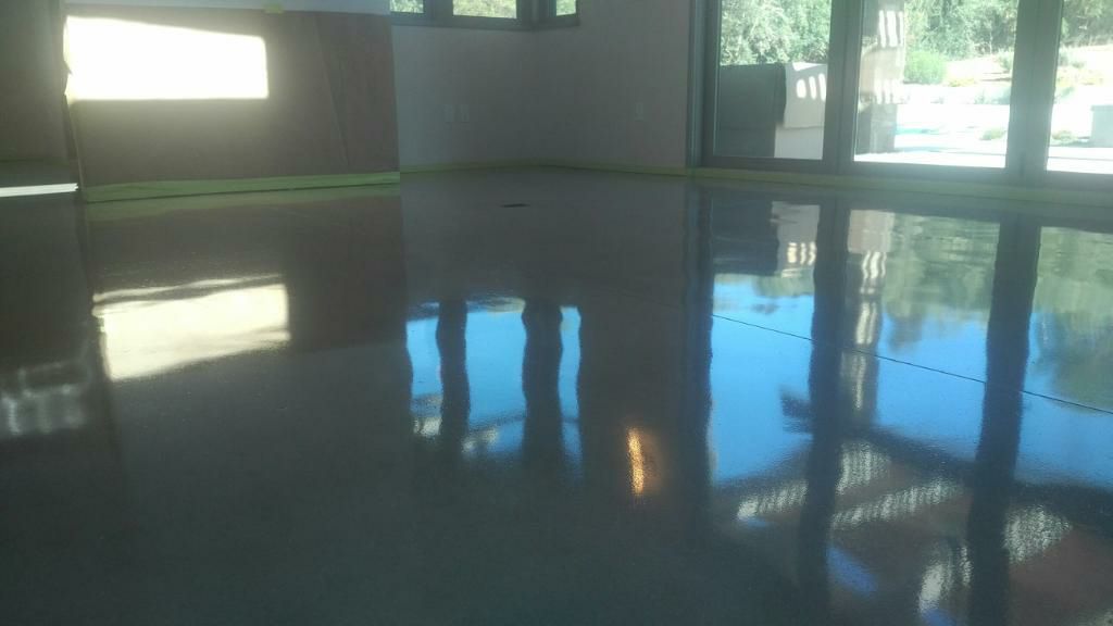 Reflective gray epoxy floor in a room, reflecting light from windows and trees.
