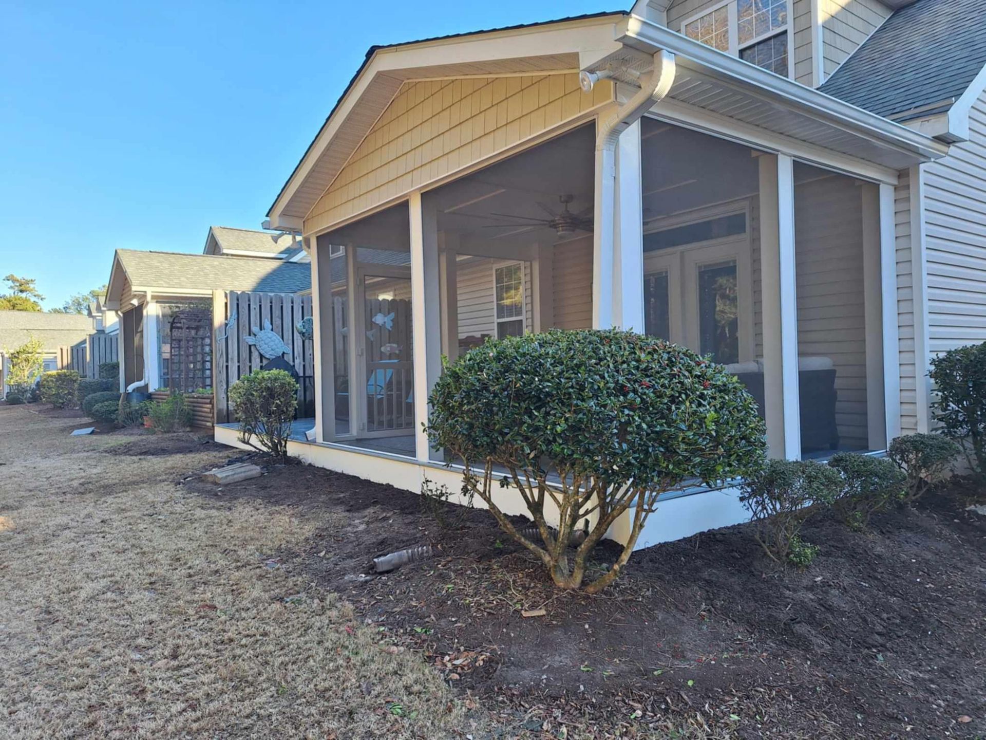 A house with a screened in porch and a tree in front of it.