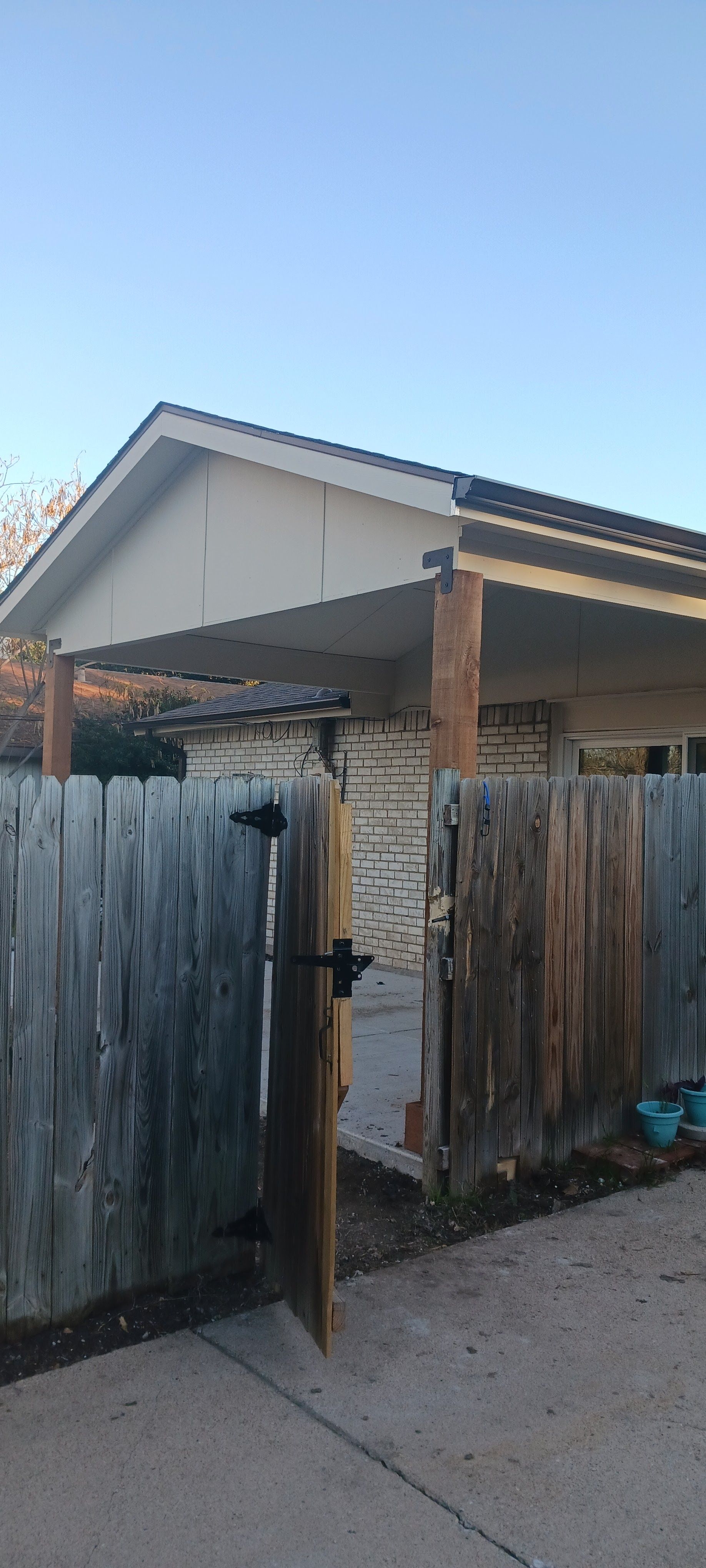 A house with a carport and a wooden fence in front of it.