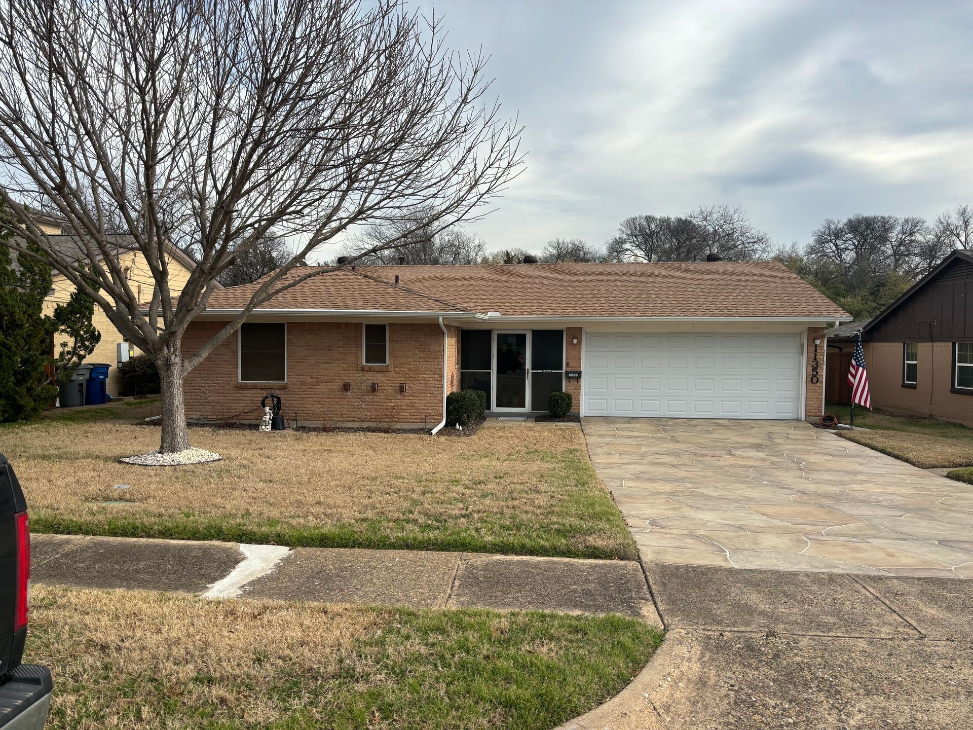 A brick house with a white garage door and a red truck parked in front of it.
