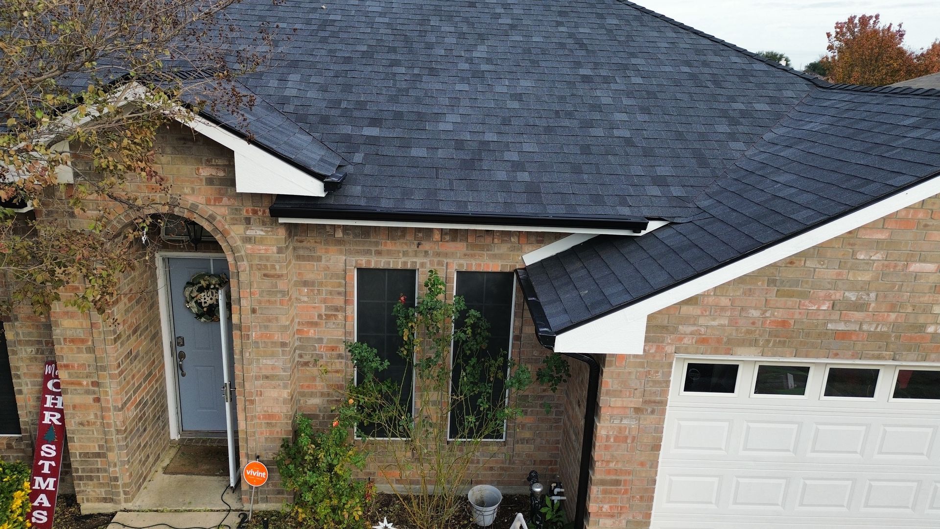 Brick house with dark roof and white trim. Front door under an arched entrance, white garage door to the right.