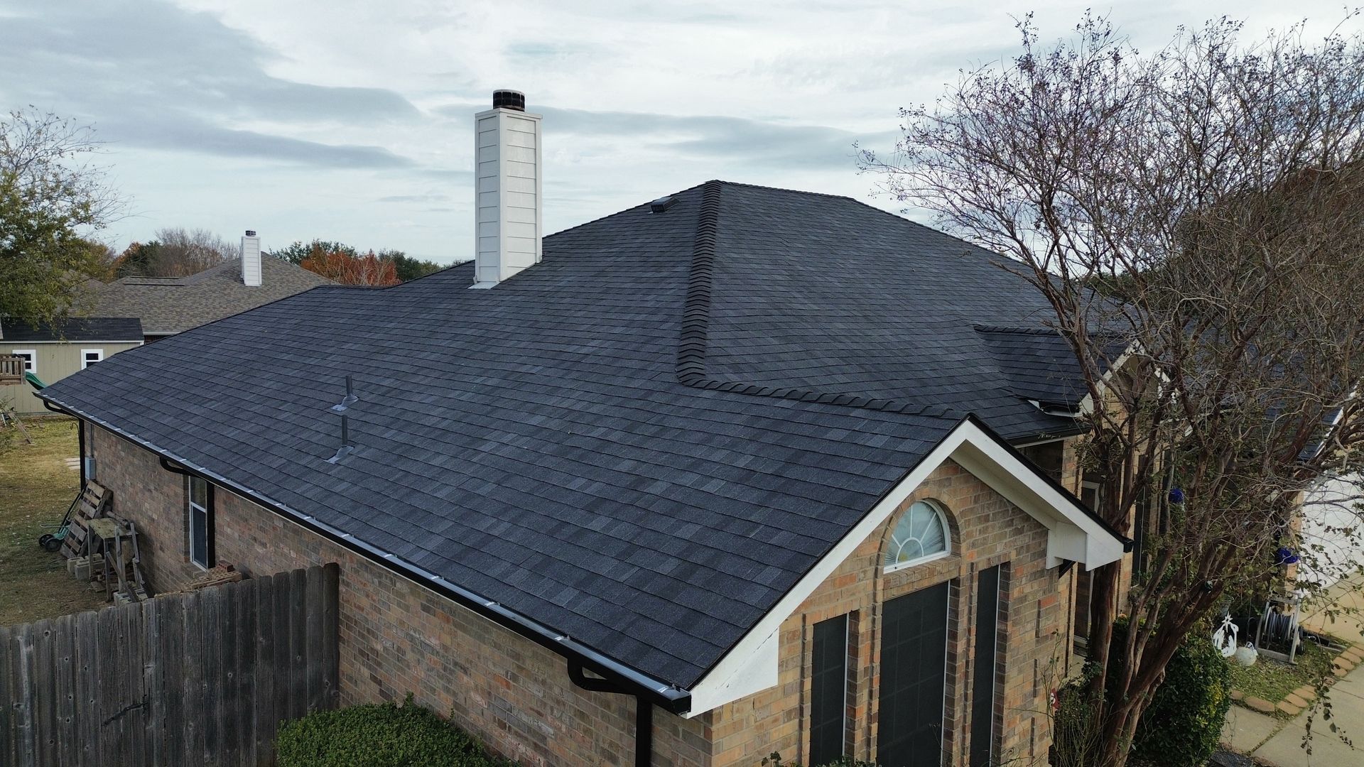 House with dark blue roof and white chimney under an overcast sky.