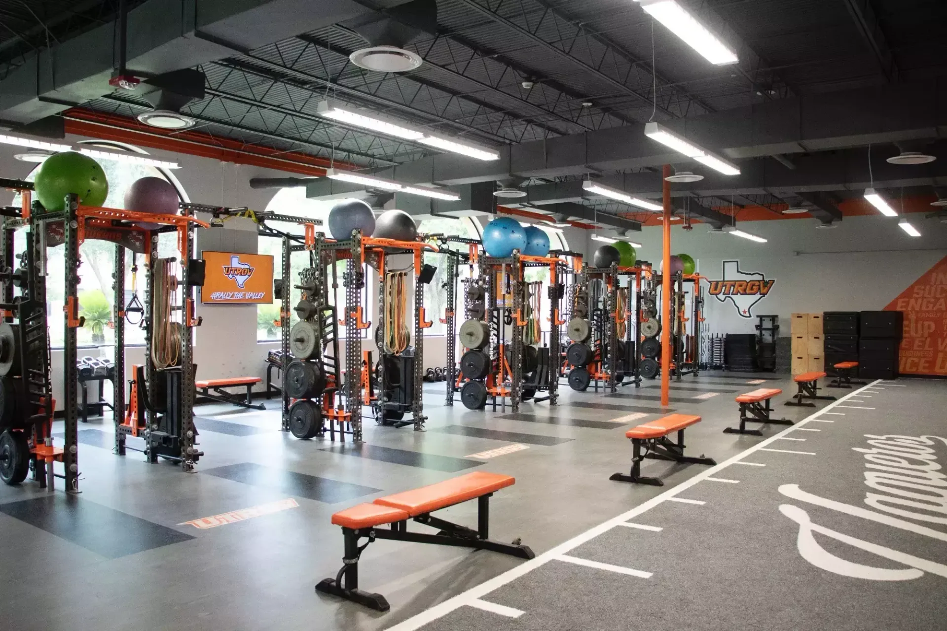 A large gym filled with lots of exercise equipment and benches.