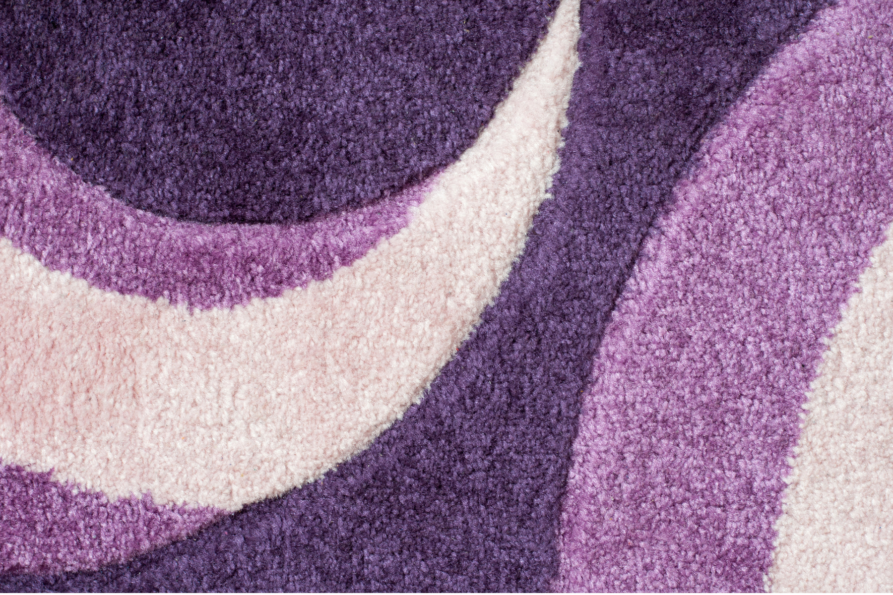 A close up of a purple and white rug with a swirl pattern.