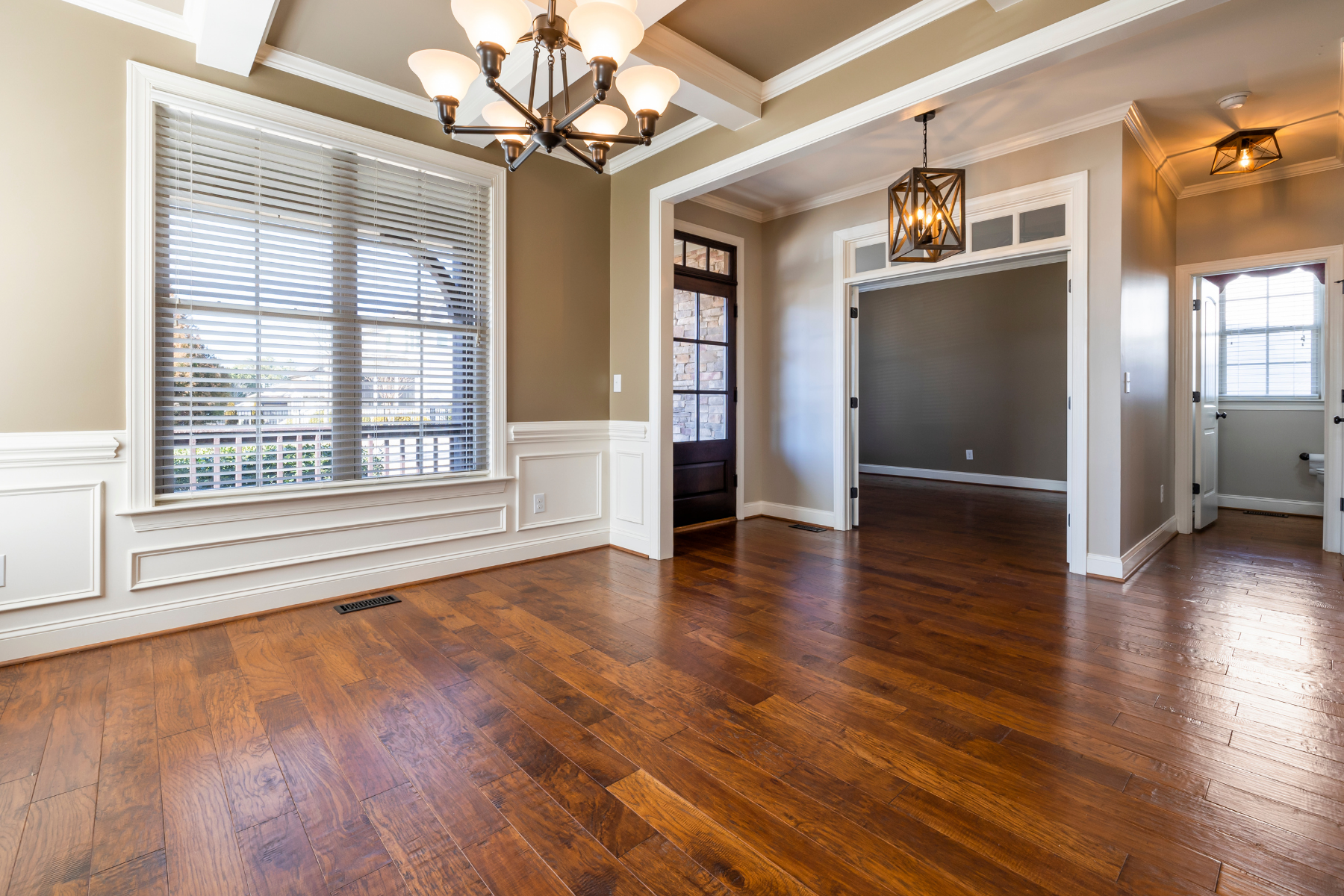 An empty living room with hardwood floors and a chandelier.