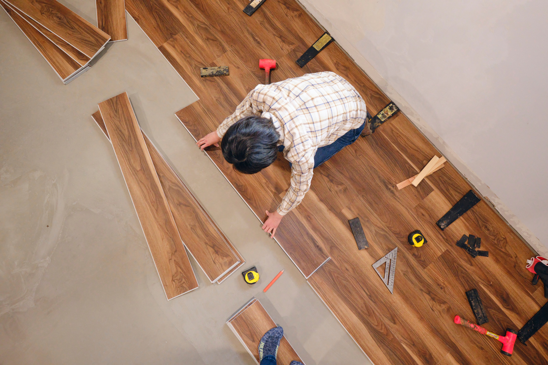 A man is installing a wooden floor in a room.