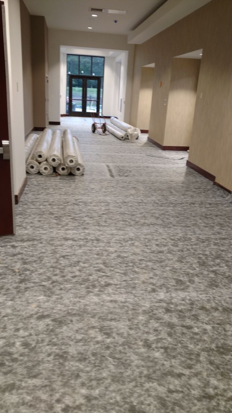 A hallway with rolls of carpet on the floor.