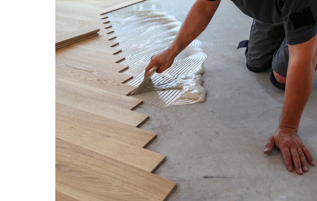 A man is applying glue to a wooden floor.
