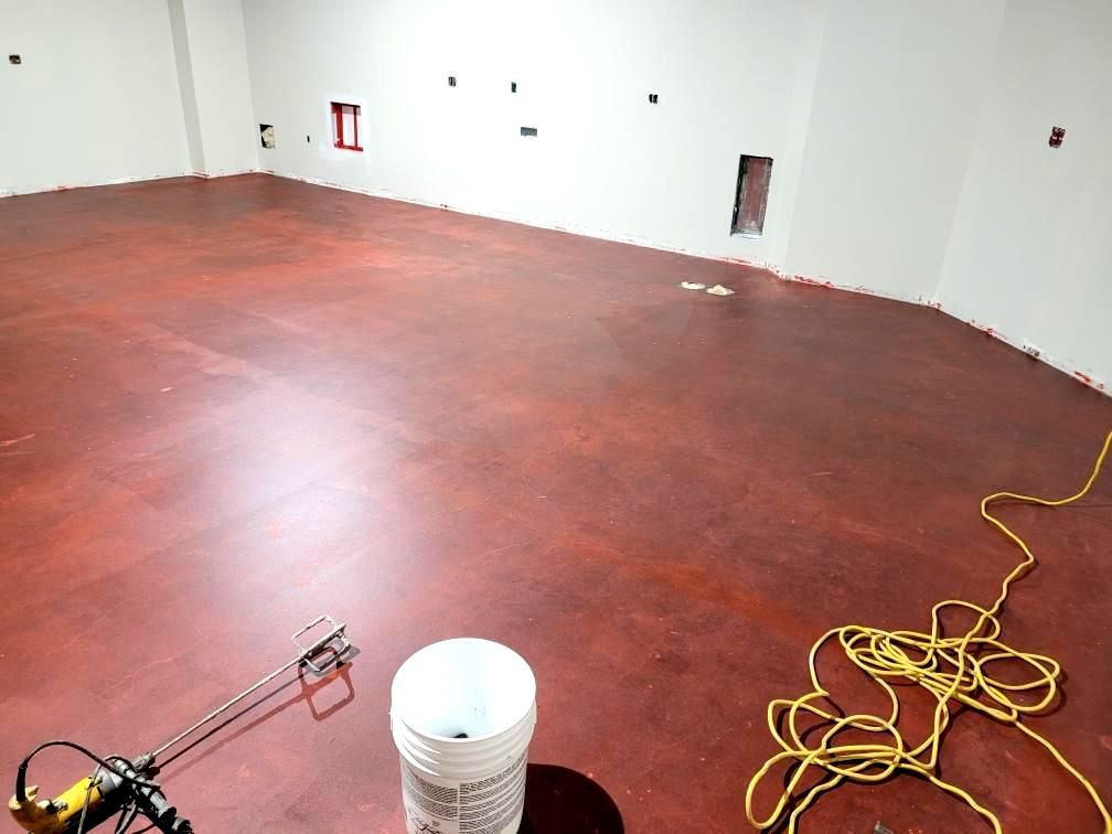 A bucket of paint is sitting on a table in an empty room with unfinished floors