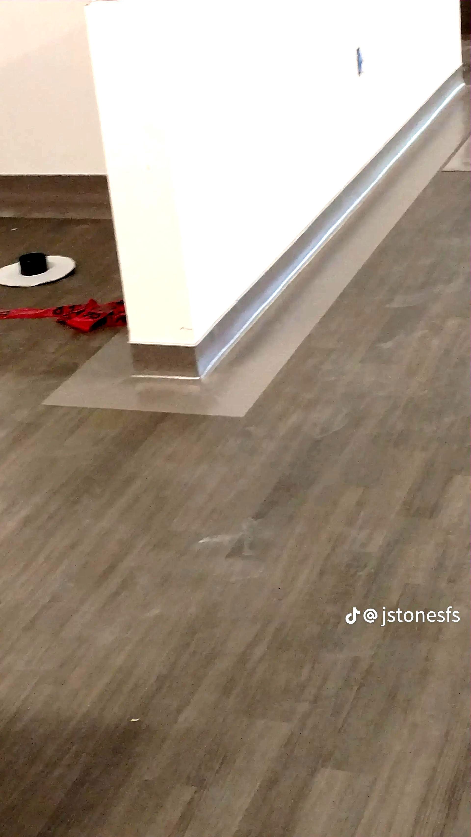 A person is standing on a wooden floor next to a wall.