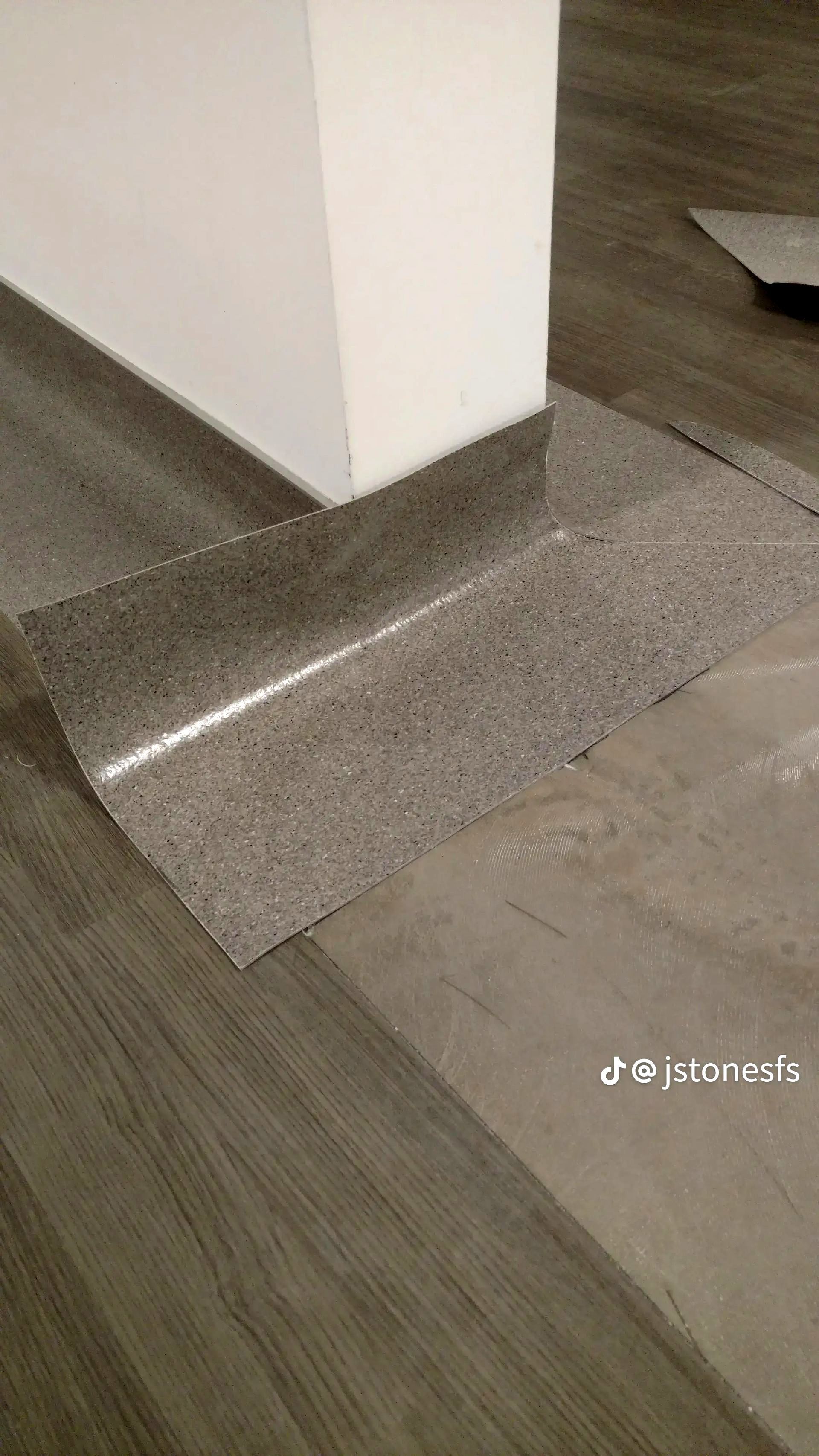 A corner of a room with a gray floor and a white wall.