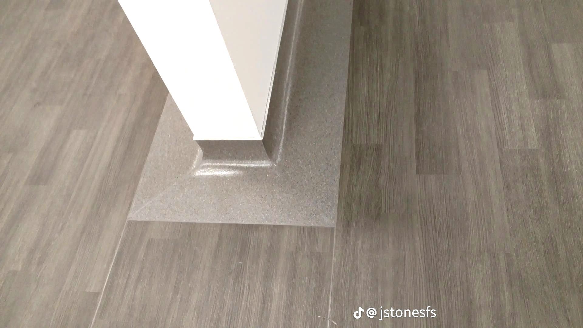 A corner of a room with a gray floor and a white wall.