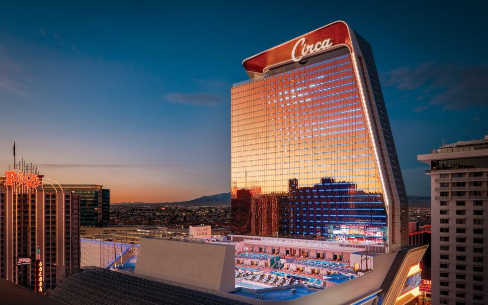 A large building with a pool in front of it is lit up at night.